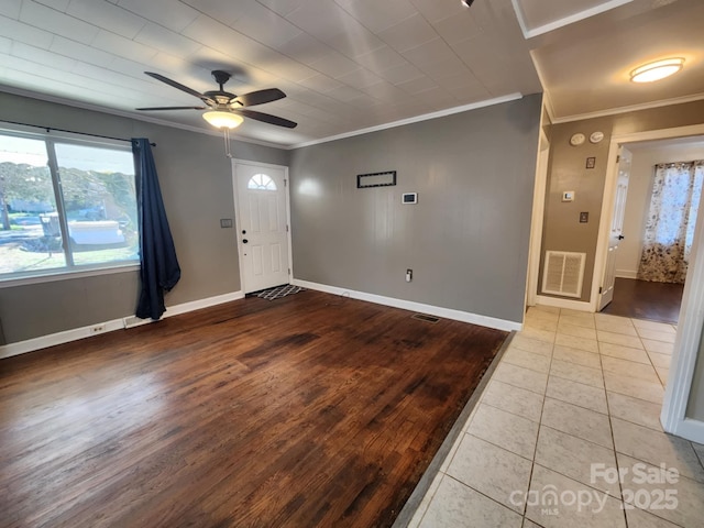 tiled foyer with ceiling fan and crown molding