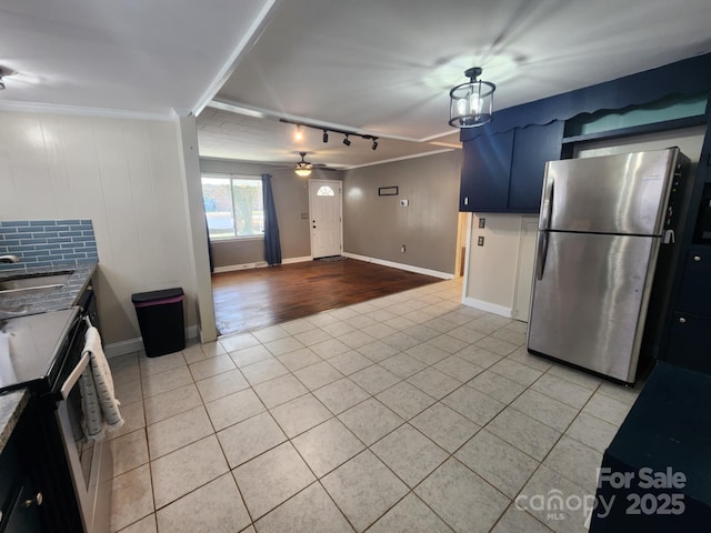 kitchen with blue cabinetry, stainless steel refrigerator, sink, range with electric stovetop, and light tile patterned floors