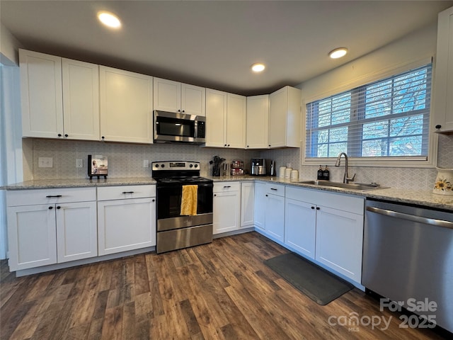 kitchen featuring sink, dark wood-type flooring, stainless steel appliances, white cabinets, and light stone counters