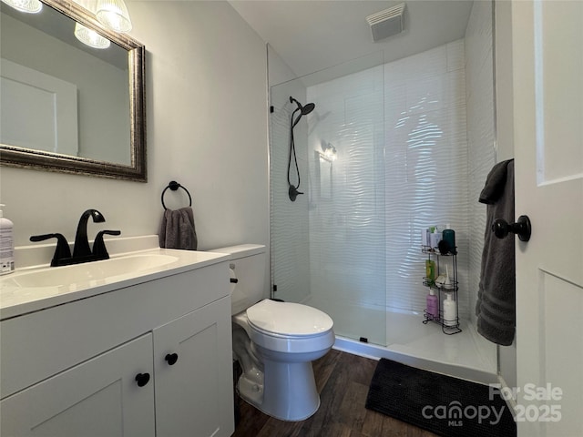 bathroom featuring vanity, toilet, hardwood / wood-style floors, and tiled shower