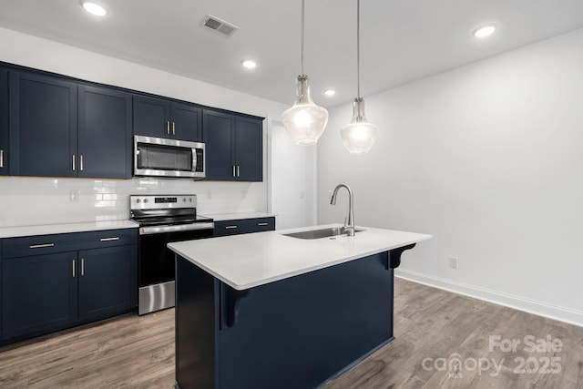 kitchen featuring sink, hanging light fixtures, an island with sink, and appliances with stainless steel finishes