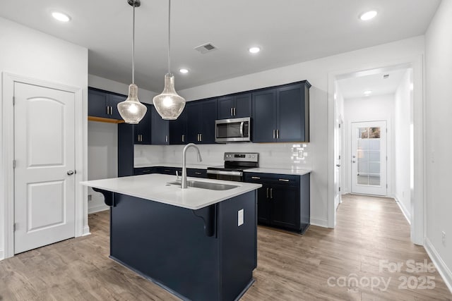 kitchen featuring sink, decorative light fixtures, a center island with sink, appliances with stainless steel finishes, and a kitchen breakfast bar