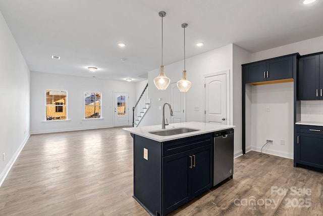 kitchen featuring decorative light fixtures, dishwasher, an island with sink, sink, and light hardwood / wood-style floors