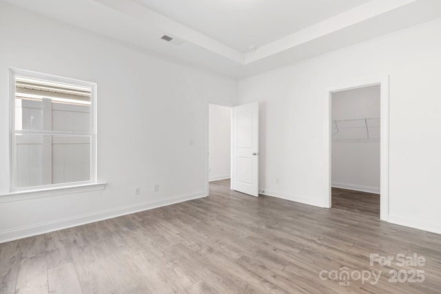 unfurnished bedroom with a walk in closet, hardwood / wood-style floors, and a closet