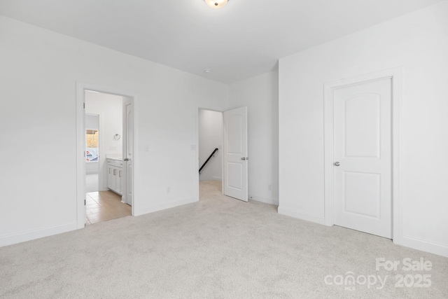 unfurnished bedroom with carpet floors, baseboards, and ensuite bathroom