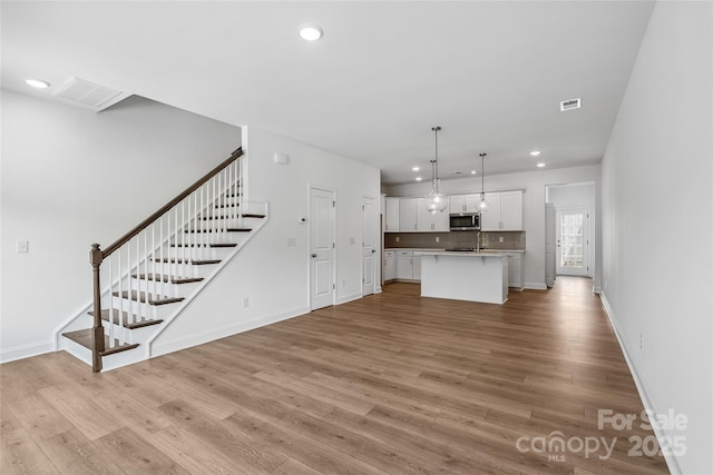 143 Cherry Springs Ln Unit 13-C, Asheville, NC 28804 - unfurnished living room with light wood-style flooring, recessed lighting, and stairway