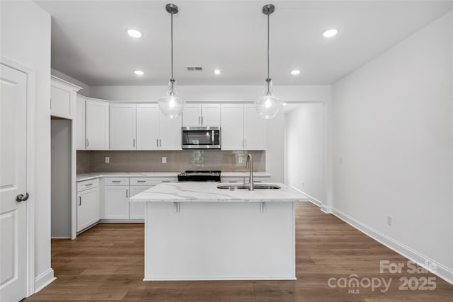 143 Cherry Springs Ln Unit 13-C, Asheville, NC 28804 - kitchen with stainless steel microwave, tasteful backsplash, white cabinetry, range, and an island with sink