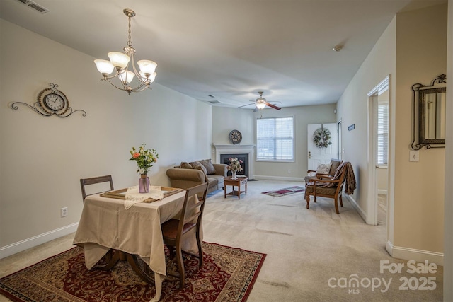 carpeted dining space with ceiling fan with notable chandelier