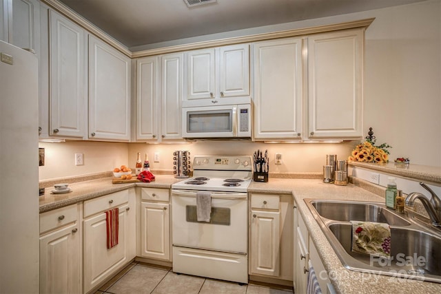 kitchen featuring cream cabinetry, white appliances, sink, and light tile patterned floors