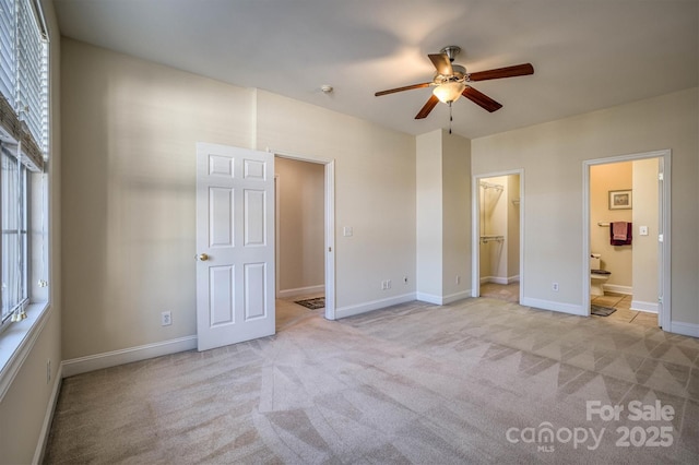 unfurnished bedroom with light carpet, ensuite bath, ceiling fan, a spacious closet, and a closet