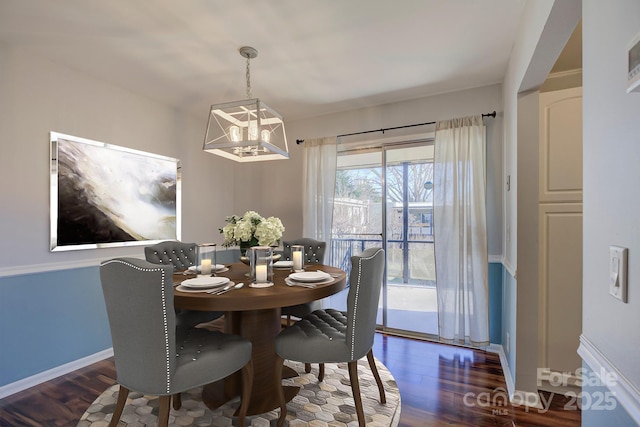 dining area featuring dark wood-type flooring and a notable chandelier