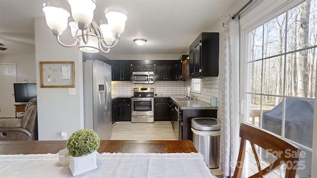 kitchen featuring a notable chandelier, sink, decorative backsplash, and stainless steel appliances