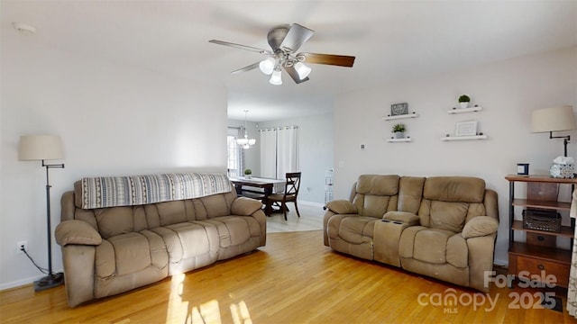 living room featuring light hardwood / wood-style flooring and ceiling fan with notable chandelier