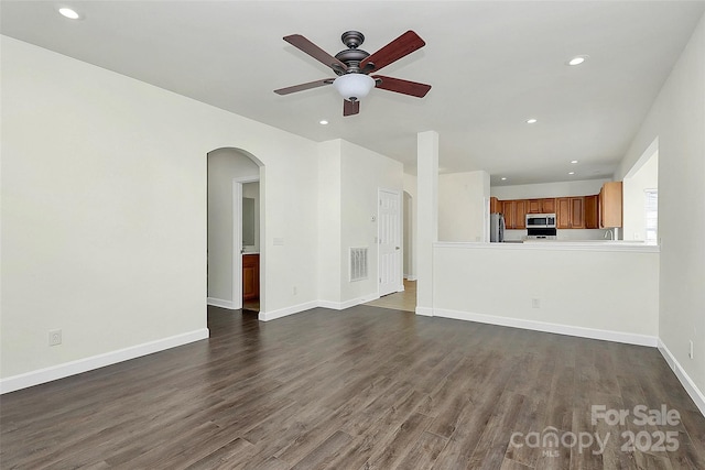 unfurnished living room featuring ceiling fan and dark wood-type flooring