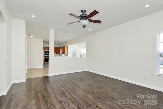 unfurnished living room with a healthy amount of sunlight, ceiling fan, and dark wood-type flooring