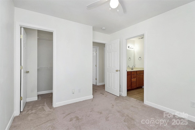 unfurnished bedroom featuring a walk in closet, ensuite bath, ceiling fan, light colored carpet, and a closet