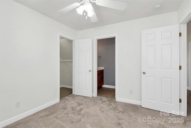 unfurnished bedroom featuring ceiling fan, light colored carpet, a walk in closet, and a closet