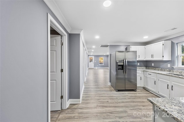 kitchen with light stone counters, white cabinets, light hardwood / wood-style floors, and stainless steel refrigerator with ice dispenser