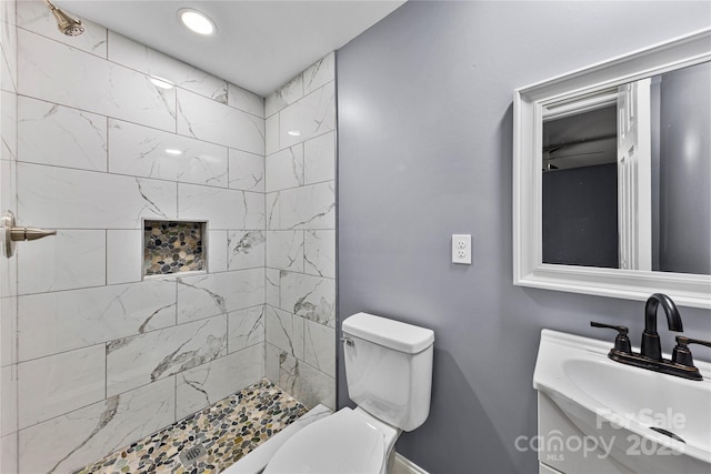 bathroom featuring vanity, toilet, and a tile shower