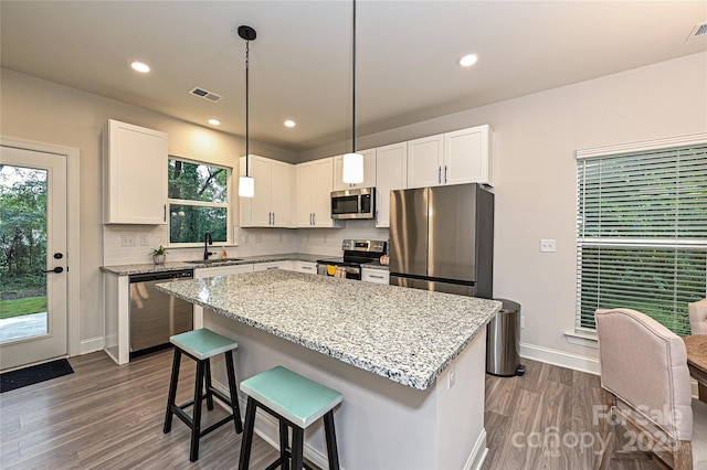 kitchen featuring a center island, hanging light fixtures, white cabinets, and stainless steel appliances