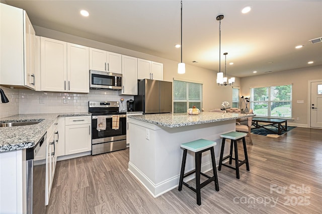 kitchen featuring white cabinetry, a center island, sink, stainless steel appliances, and light hardwood / wood-style floors