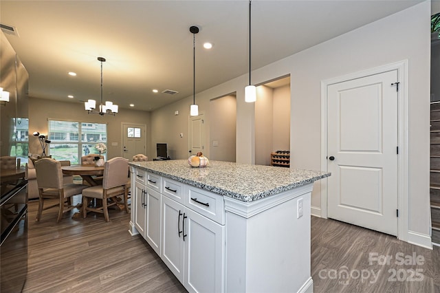 kitchen with white cabinets, a center island, hanging light fixtures, and dark wood-type flooring