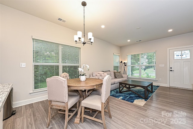 dining area featuring wood-type flooring and an inviting chandelier