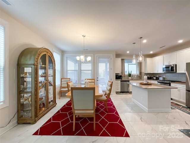 tiled dining area with a notable chandelier and a healthy amount of sunlight