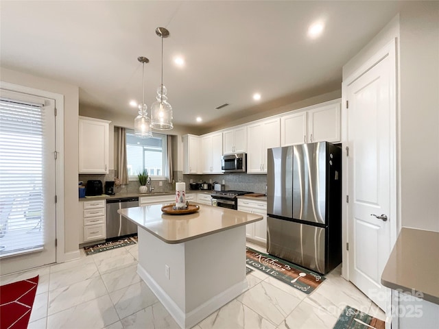 kitchen with sink, a center island, pendant lighting, white cabinets, and appliances with stainless steel finishes