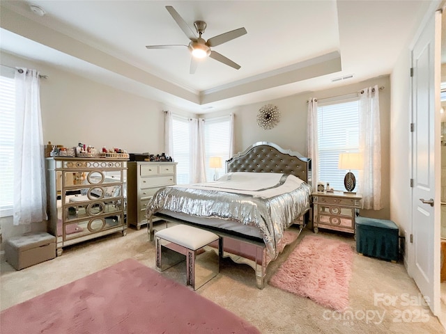 bedroom featuring light carpet, a raised ceiling, ceiling fan, and crown molding