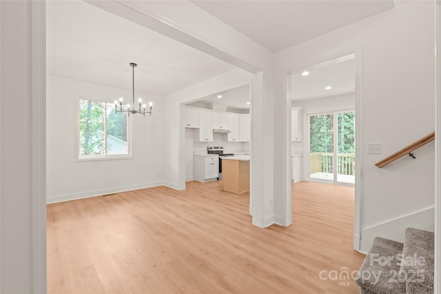 unfurnished living room with light wood-type flooring and a notable chandelier