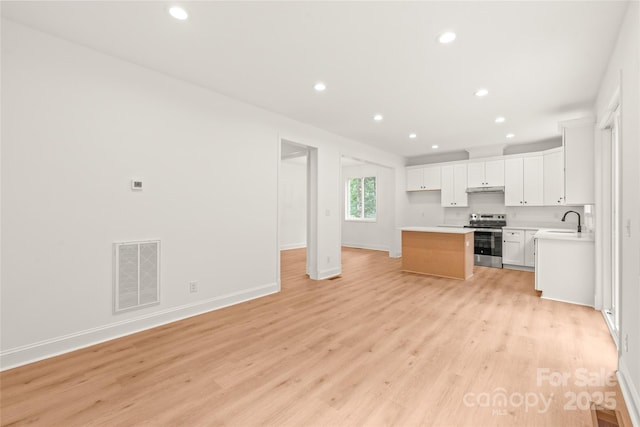 kitchen with light hardwood / wood-style flooring, white cabinetry, stainless steel electric stove, and sink