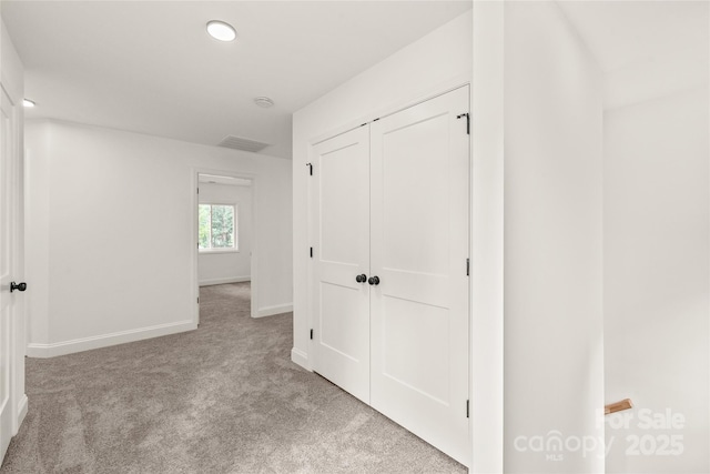 hallway featuring light colored carpet