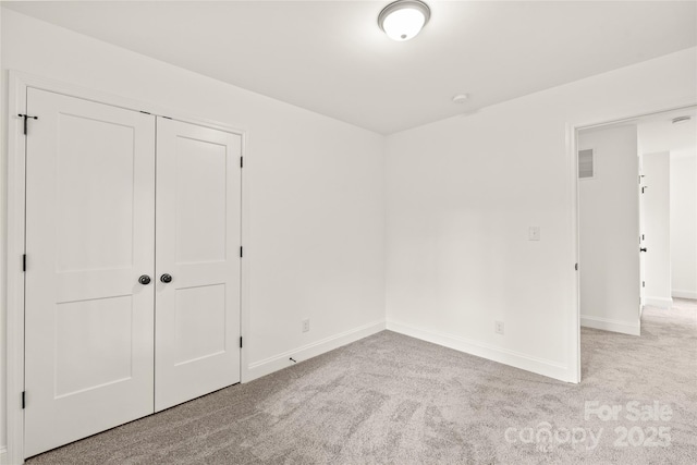 unfurnished bedroom with light carpet and a closet