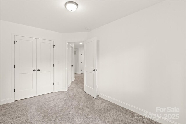 unfurnished bedroom with light colored carpet and a closet