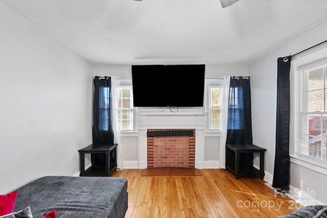 living room with a fireplace, a textured ceiling, light wood-type flooring, and plenty of natural light