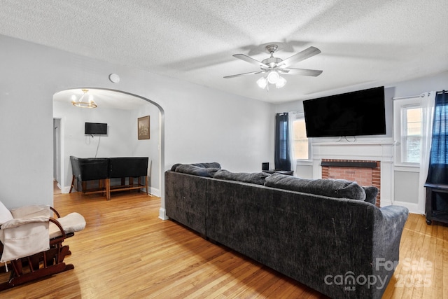 living room featuring a fireplace, hardwood / wood-style floors, a textured ceiling, and ceiling fan