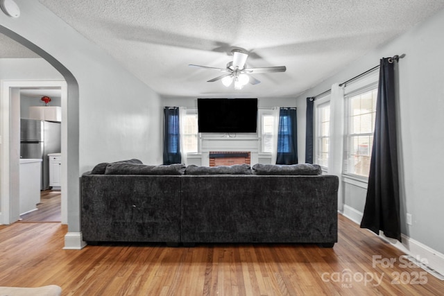 living room featuring ceiling fan, a textured ceiling, and hardwood / wood-style flooring