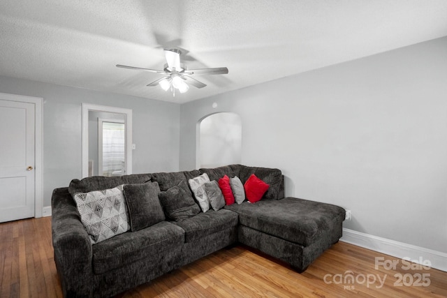 living room featuring hardwood / wood-style flooring, ceiling fan, and a textured ceiling