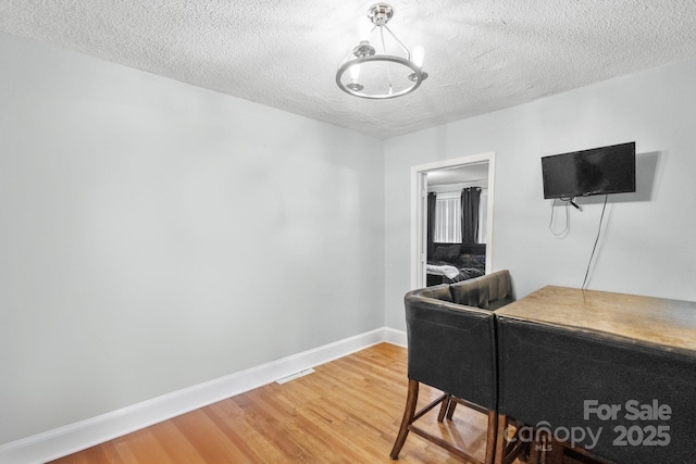 office area with hardwood / wood-style floors, a textured ceiling, and an inviting chandelier