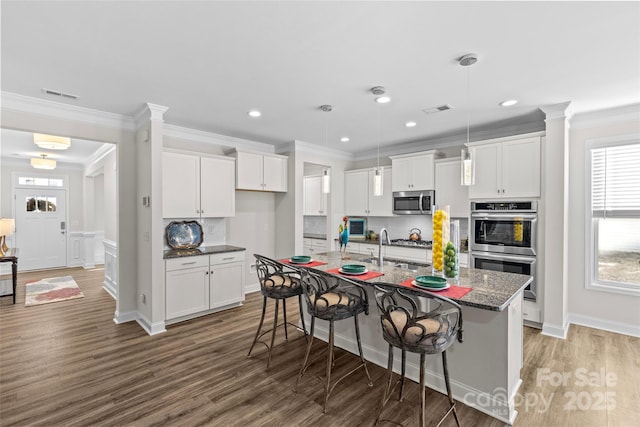 kitchen with white cabinets, appliances with stainless steel finishes, and a center island with sink