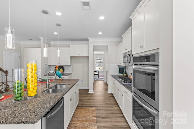 kitchen featuring white cabinets, a center island with sink, sink, hanging light fixtures, and appliances with stainless steel finishes