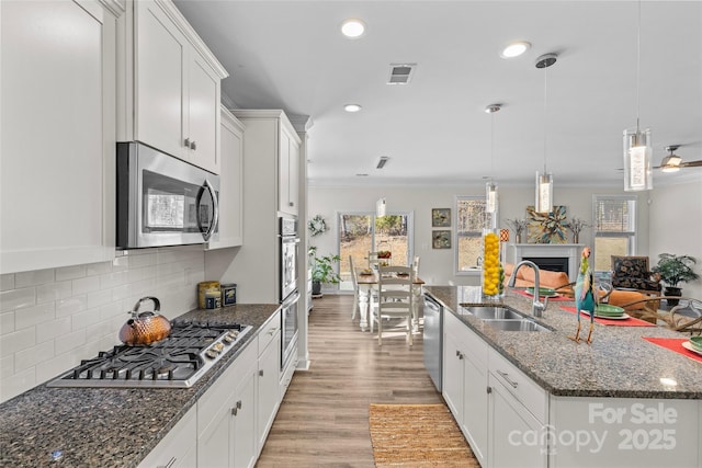 kitchen featuring crown molding, white cabinetry, stainless steel appliances, and hanging light fixtures