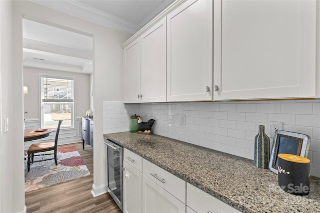 kitchen with white cabinetry, light stone countertops, wine cooler, hardwood / wood-style floors, and ornamental molding