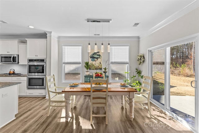 kitchen featuring white cabinets, crown molding, stainless steel appliances, and hanging light fixtures