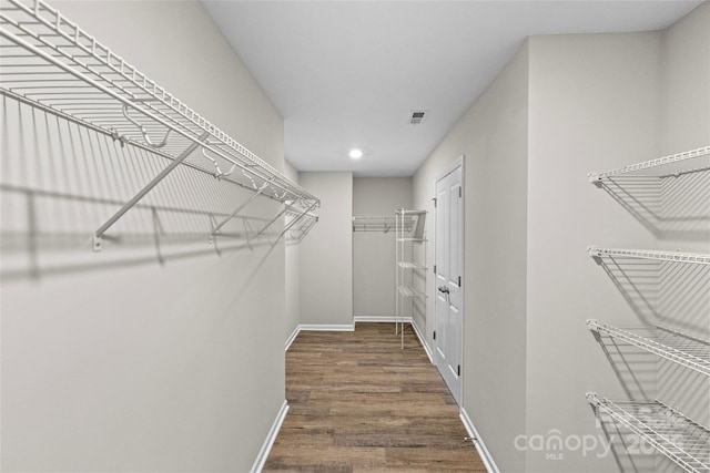 walk in closet with dark wood-type flooring