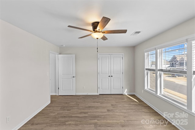 unfurnished bedroom featuring ceiling fan, a closet, and light wood-type flooring