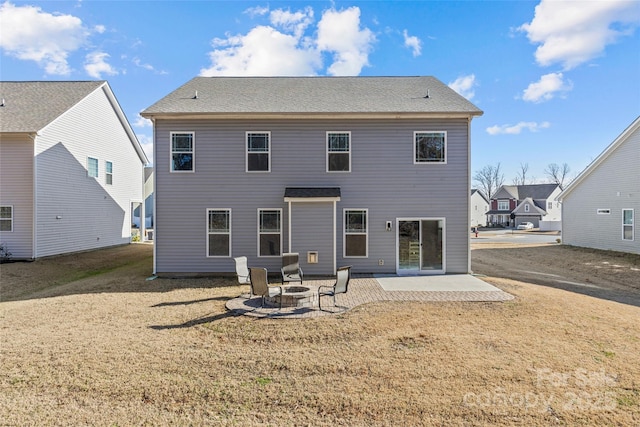 back of property with a lawn, a patio area, and a fire pit