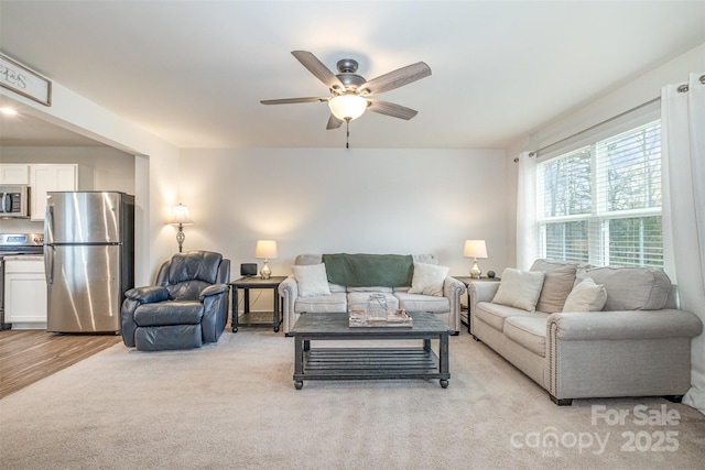 carpeted living room with ceiling fan