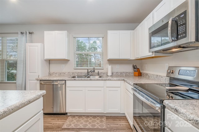 kitchen with sink, white cabinets, stainless steel appliances, and light hardwood / wood-style flooring